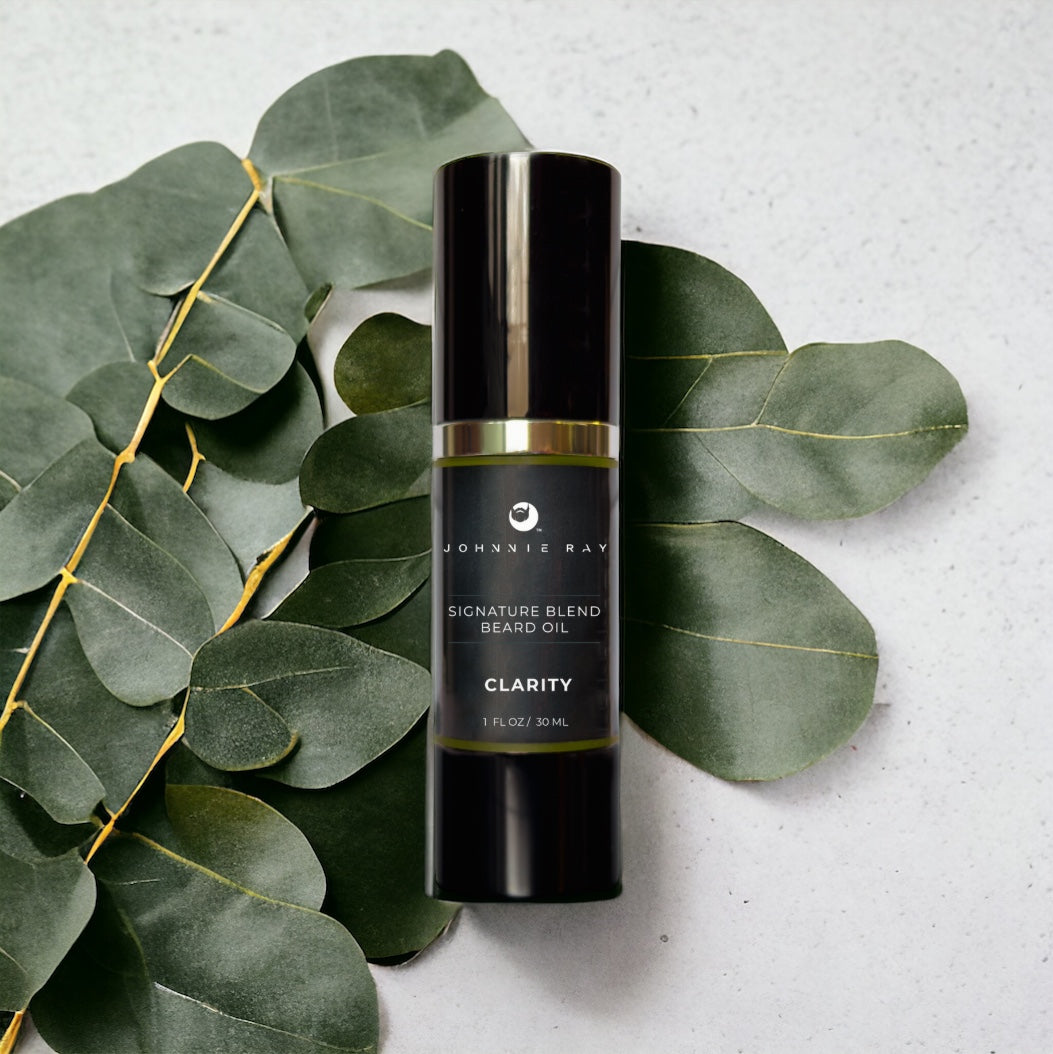 Johnnie Ray Signature Blend Beard Oil in a black airless pump top bottle on a spread of eucalyptus leaves. 