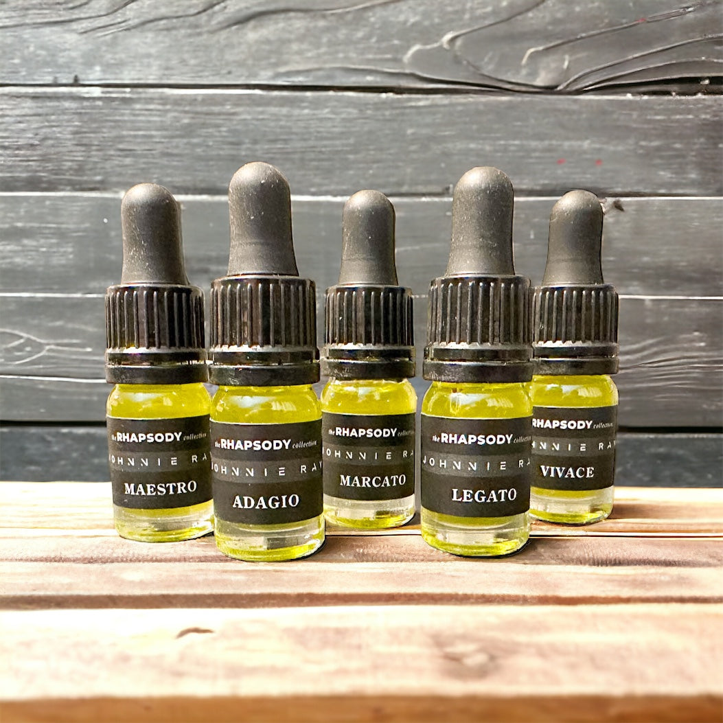 5mL bottles of The Rhapsody Collection Signature Blend Beard Oil from Johnnie Ray sitting on a wooden table