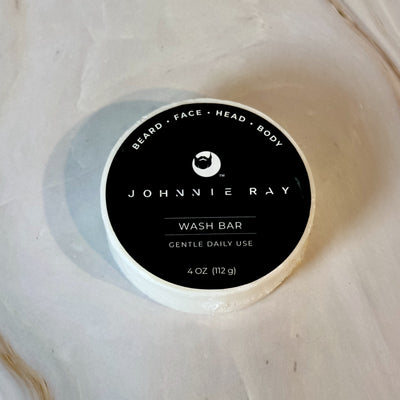 4 oz round Johnnie Ray wash bar with black label laying on marble countertop