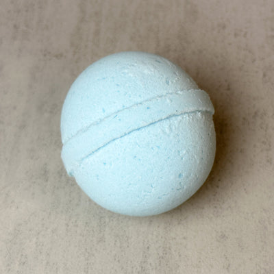 Blue Johnnie Ray Frost bath bomb against concrete background.