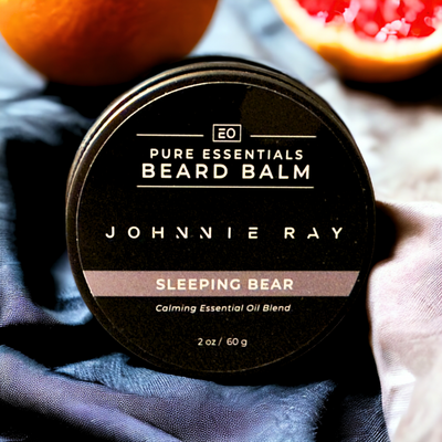 Johnnie Ray Pure Essentials Sleeping Bear Beard Balm stacked on blue silky fabric with grapefruit in background