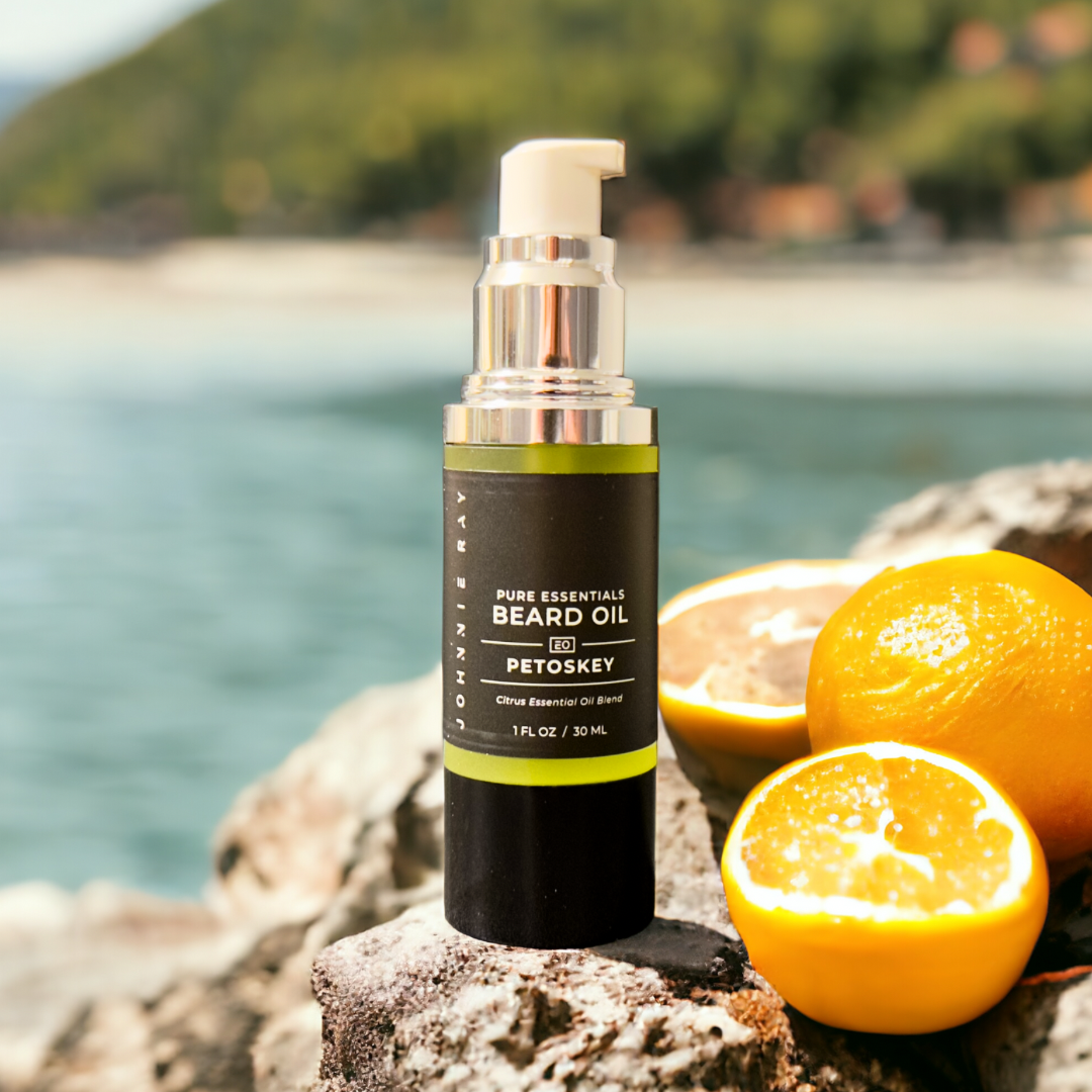 Bottle of Johnnie Ray Petoskey Beard Oil on rock in front of a lake with citrus fruits