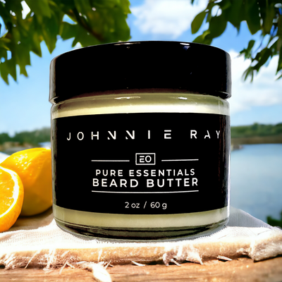 Jar of Johnnie Ray Petoskey Beard Butter stacked on outdoor table in front of a lake with citrus fruit