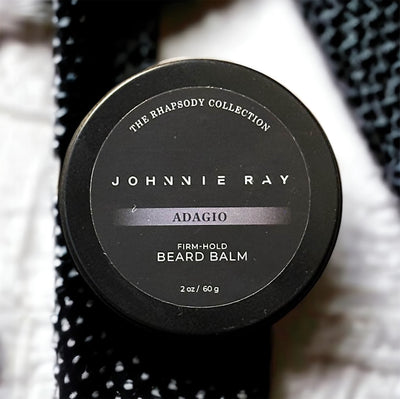 Johnnie Ray Adagio Beard Balm from The Rhapsody Collection in a black tin displayed on textured fabric