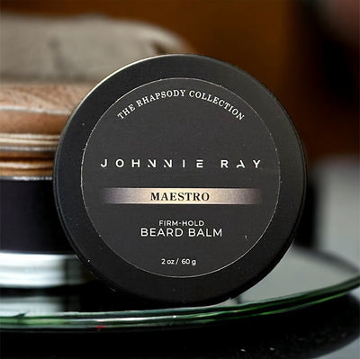 Johnnie Ray Maestro Beard Balm from The Rhapsody Collection in a black tin displayed on green glass display