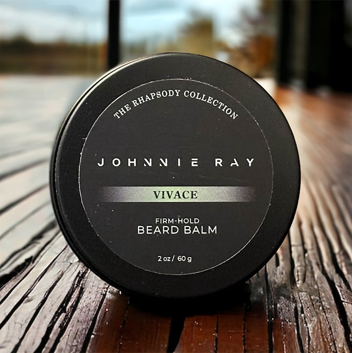 Johnnie Ray Vivace Beard Balm from The Rhapsody Collection in a black tin displayed on dark rustic wood