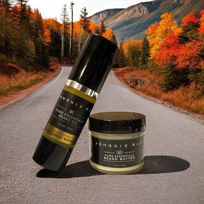 Johnnie Ray Pictured Rocks Beard Oil Bottled leaned against a jar of Pictured Rocks Beard Butter on a dirt road with fall foliage in background