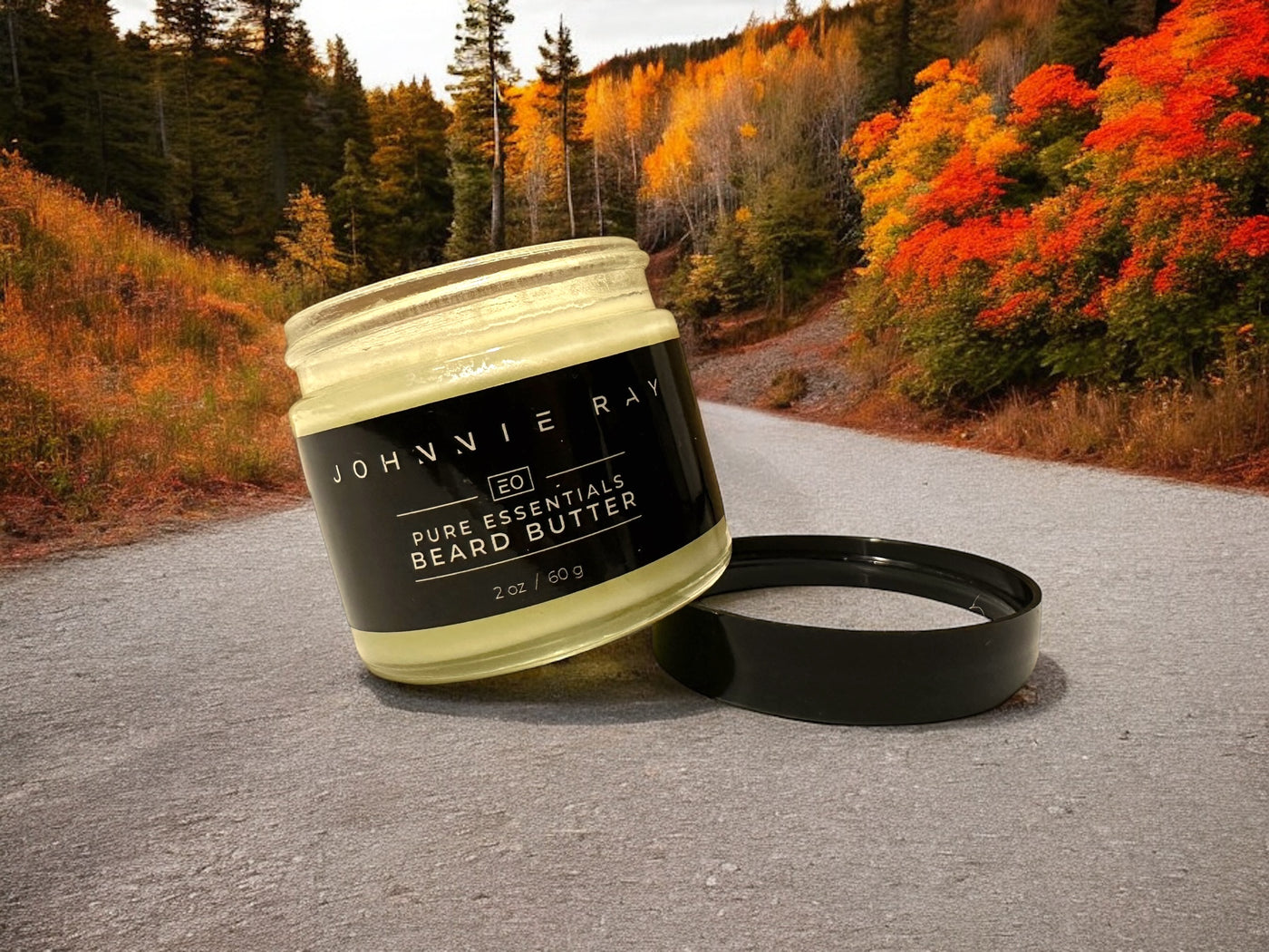 Johnnie Ray Pictured Rocks Beard Butter jar with open lid on dirt road with fall foliage in background