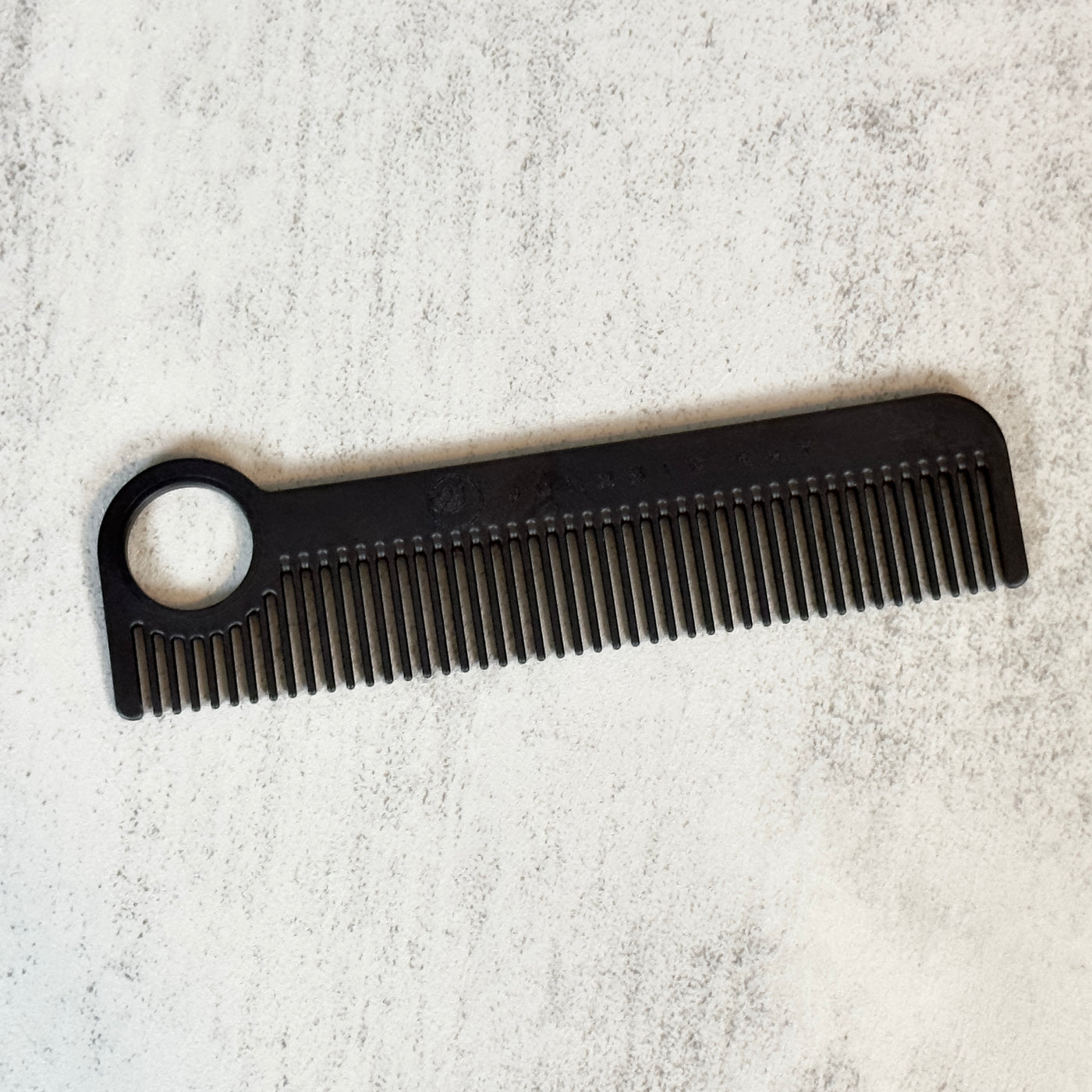 Black Chicago Comb Model 1 laid at an angle against concrete background.