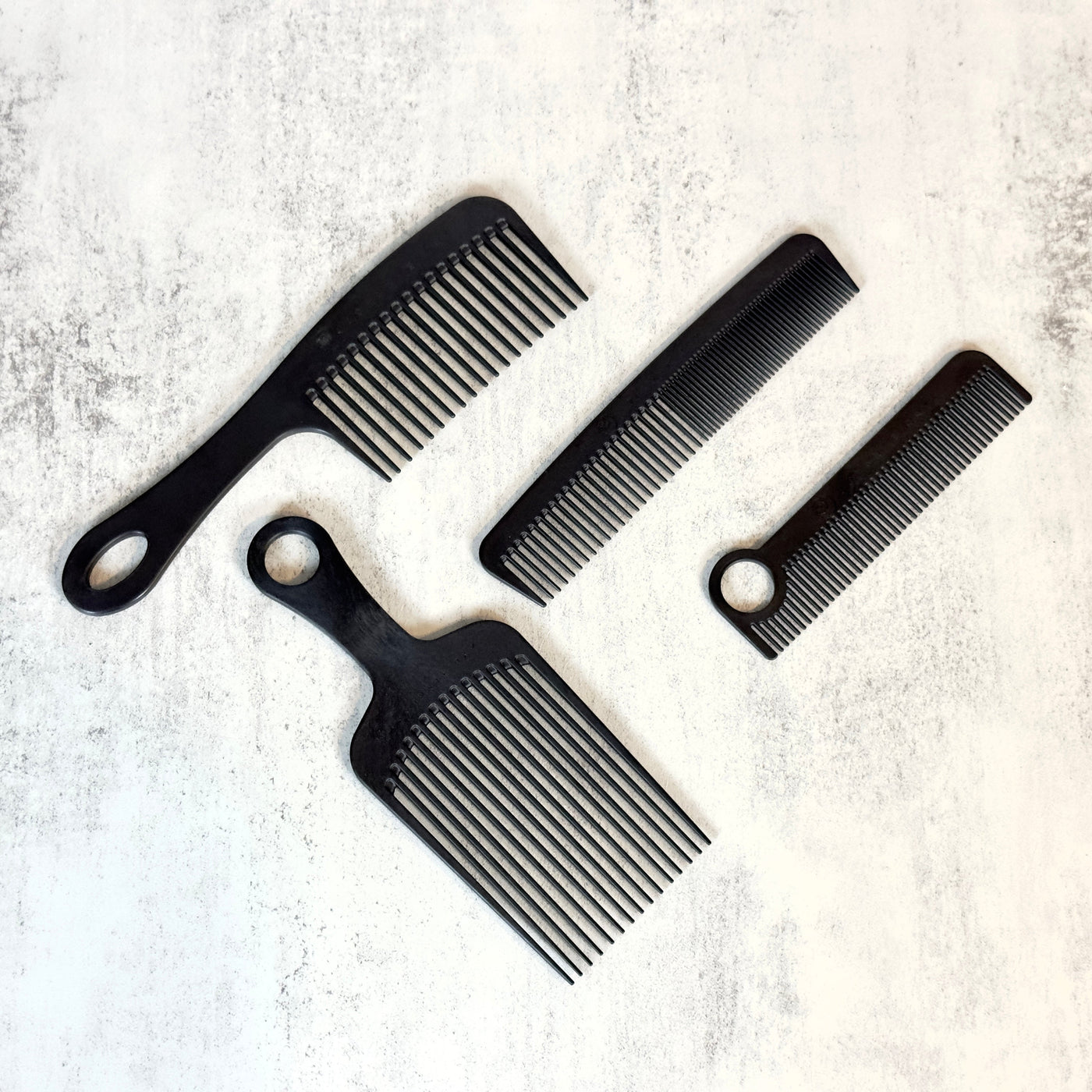 4 black Chicago Comb models arranged against concrete background.