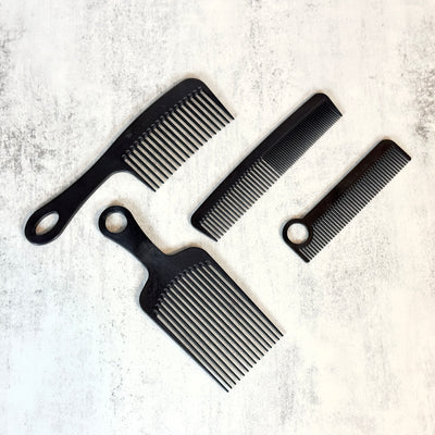 4 Black Chicago Comb beard combs arranged against concrete background.